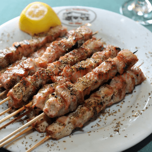A dish with a souvlaki and other food